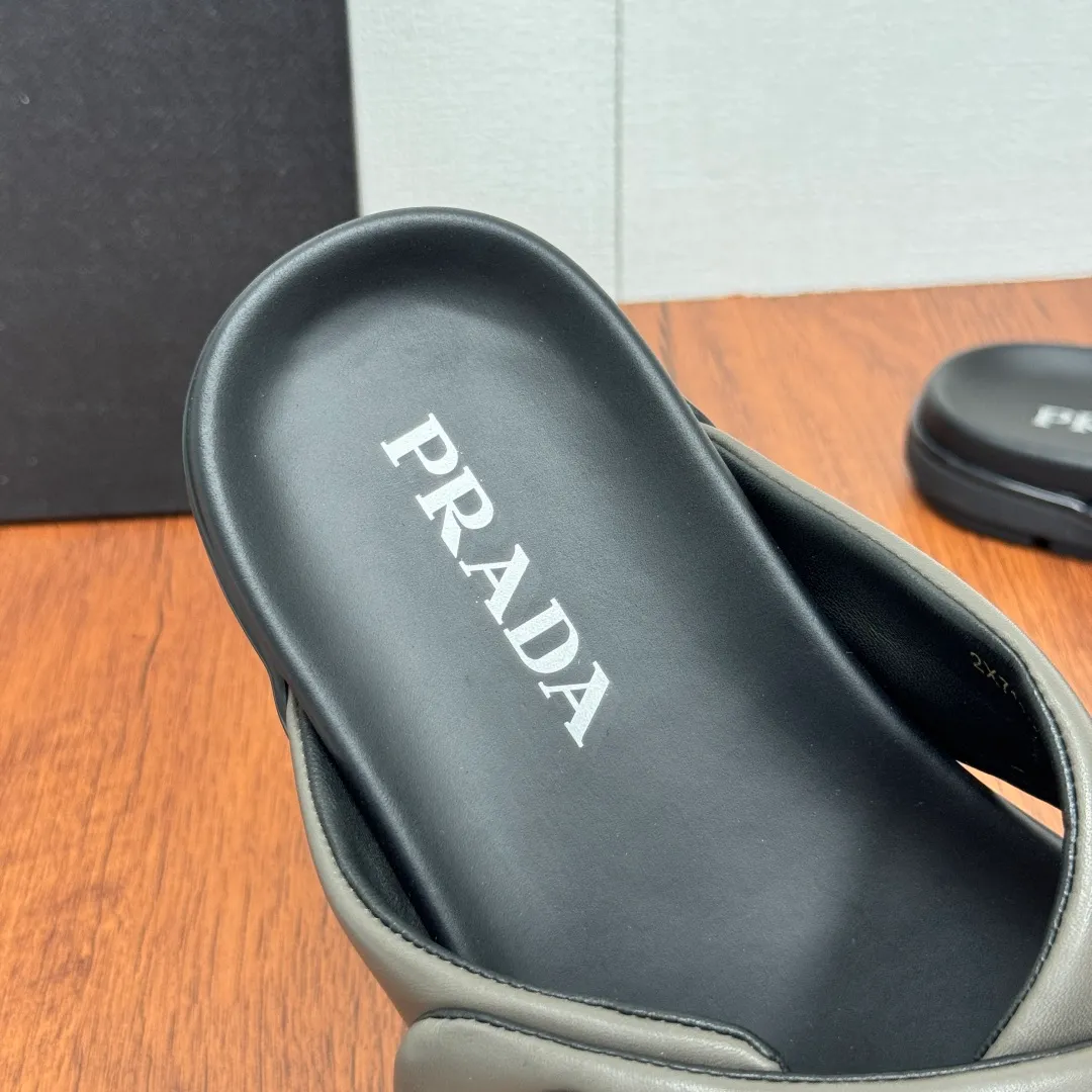 Batch 580 Prada/Prada's new men's leather cross slippers. Velcro closure can finely adjust the size. Calf leather light luxury slippers. Thick soft calf leather wraps the upper. Fat but soft rubber lazy style, soft and comfortable, excellent foot feel. Genuine leather bottom layer, cross style, with a Velcro closure buckle, easy to adjust the appropriate size, and a perfect fit for the wearing experience. The enamel gold triangle logo highlights the brand's classic features. Lightweight rubber thin sole, high foot comfort! Complete package! Size: 39-40-41-42-43-44-45 Leather shoe size Item number: 2X7132 Gray